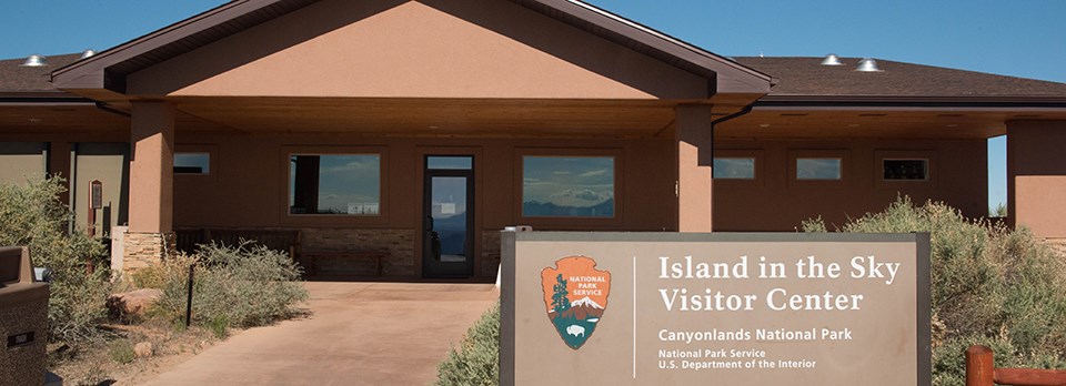 A building with a sign in front reading Island in the Sky Visitor Center Canyonlands National Park