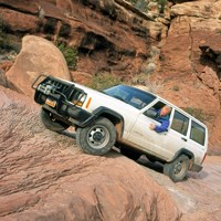A white Jeep drives up a steep slope