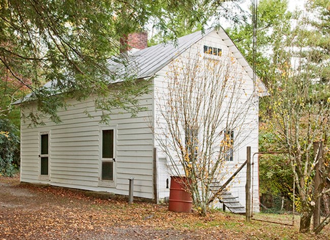 Single story white painted building with 2 doors on the front and 2 windows on the side