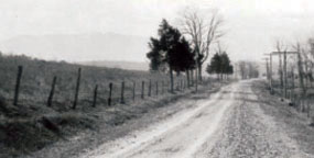 Grayscale photo of dirt road disappearing into the distance.