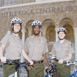 Park rangers pose with bicycles in front of Central High School.