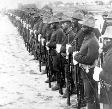 A long line of men standing with rifles in front of them