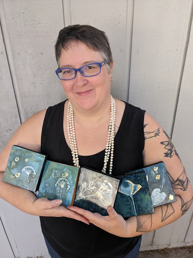 Artist Jessie Swimeley holding cyanotype prints.