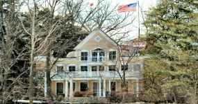 Front view of Clara Barton's Glen Echo, Maryland home during winter.  Red Cross flag and American Flag blowing in the breeze.