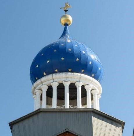 Blue onion shaped dome with gold stars. White pillars hold up the dome with a gold top with a golden colt statue on top.