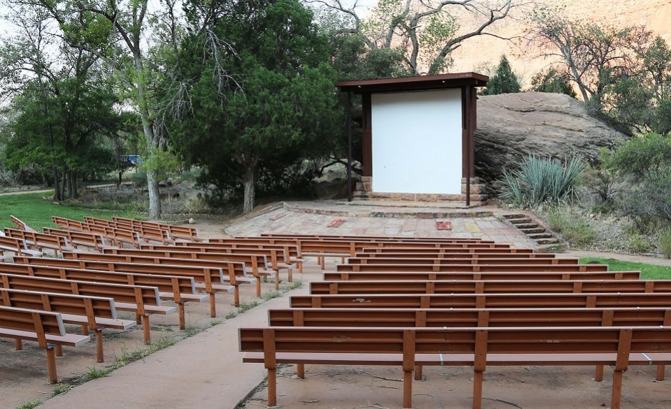 Black and white photo of rows of benches in front of a small screen with Zion Canyon in the background.