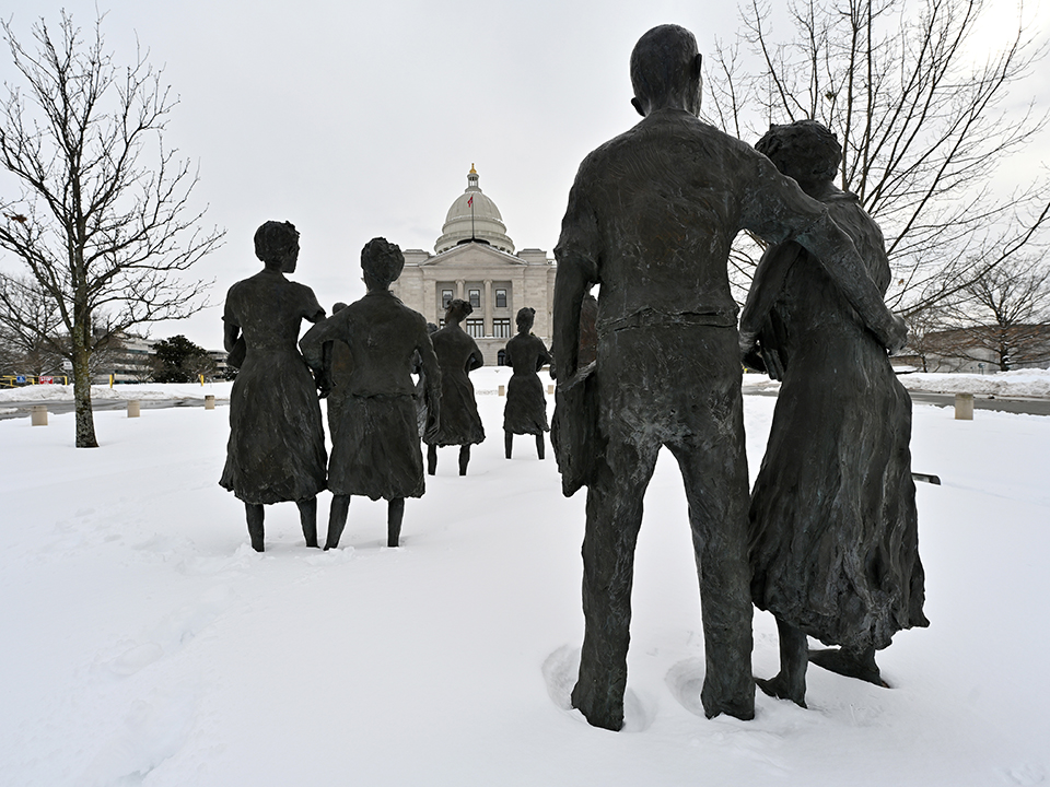 Statues of the Little Rock Nine face the Arkansas State Capitol at dusk