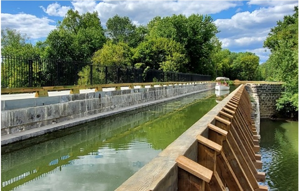A family in a canoe boat riding along the canal over the original Conococheague Aqueduct.