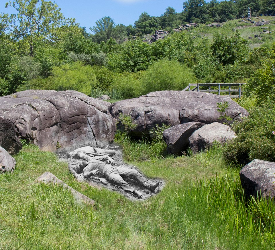 Two dead Confederate soldiers lie on the bank of a small pond, surrounded by large boulders.