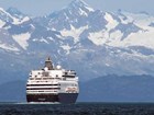 a large cruise ship on the ocean with snowy mountains in the distance