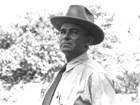 Portrait of Ed Riggs in a shirt and tie, and wearing a brimmed hat