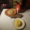 A small round heap of potatoes, a pitcher of milk, bread, and a candle 