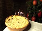 An pie/crumble style food sits in a dish in front of a christmas tree. 