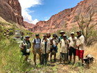 group of NPS staff and volunteers posing in front of a desert canyon