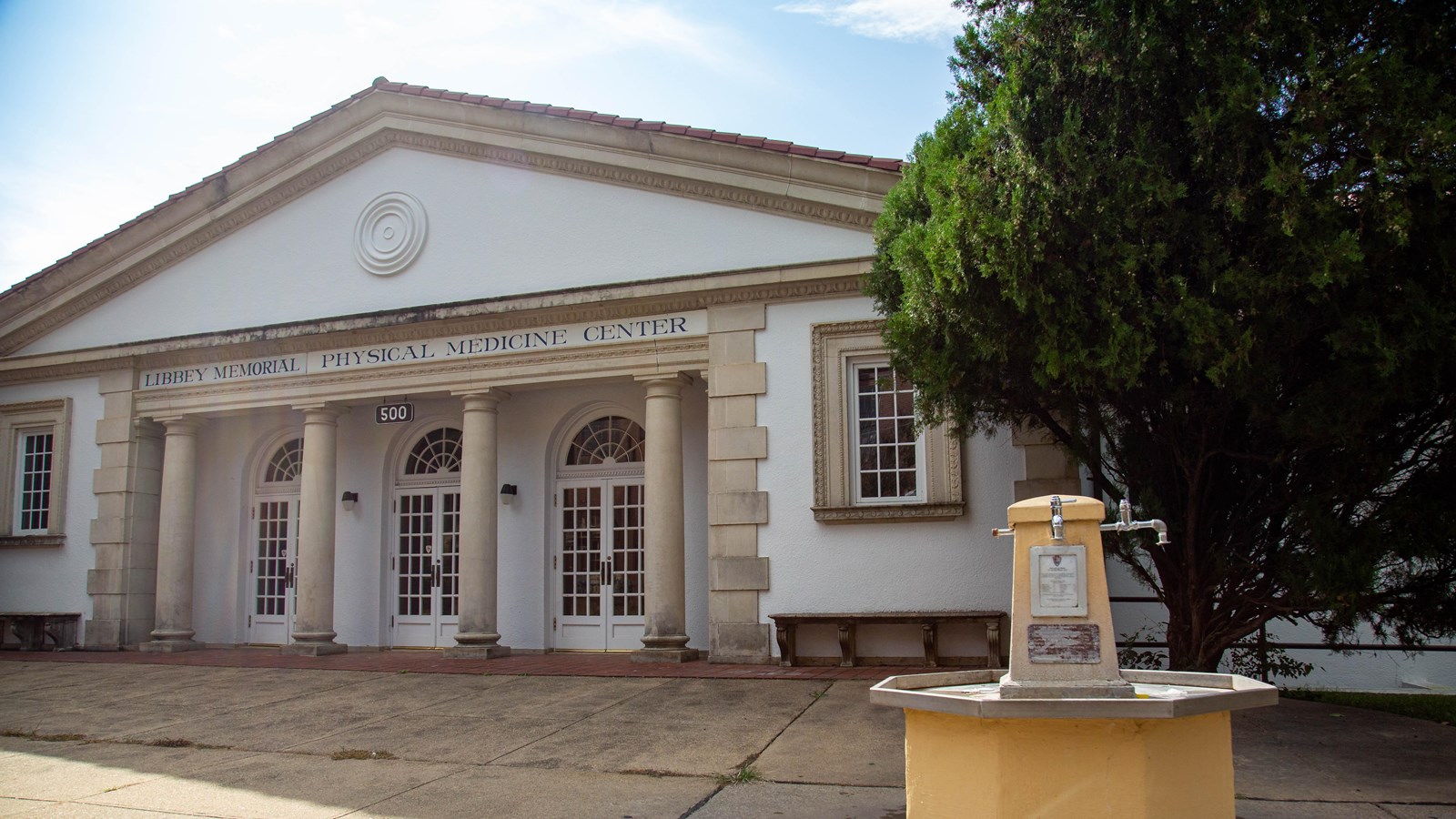 A concrete building with pillars and a pointed roof. 