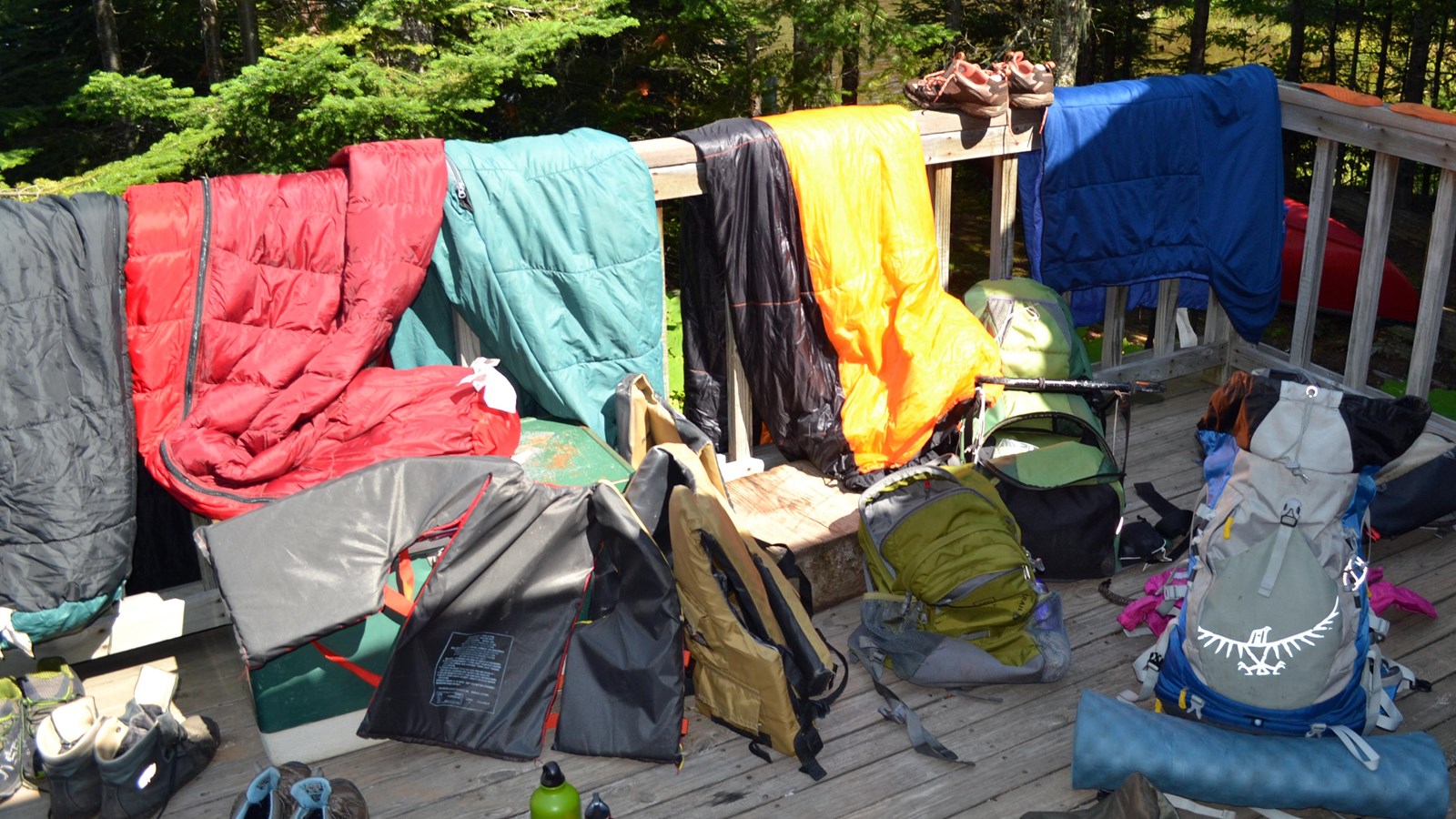Scattered camping gear hangs to dry on a porch after a backpacking trip. 