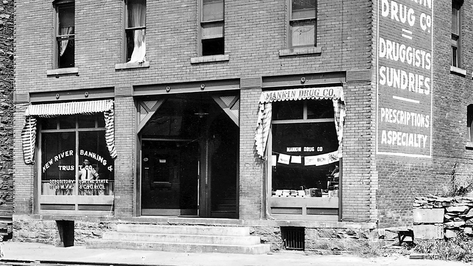 A brick building with two large glass windows and steps leading to the entrance.