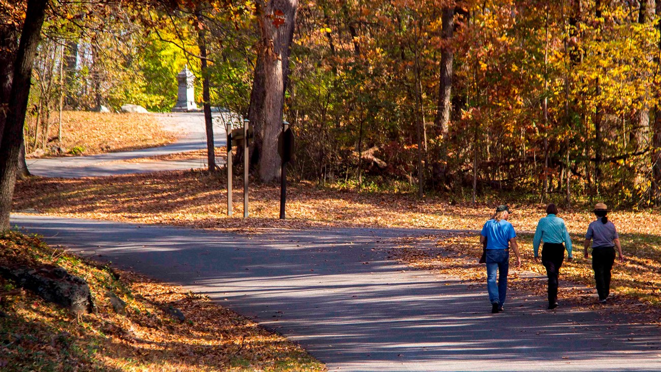 A park ranger with two visitors walking on the driving tour path at Culps Hill