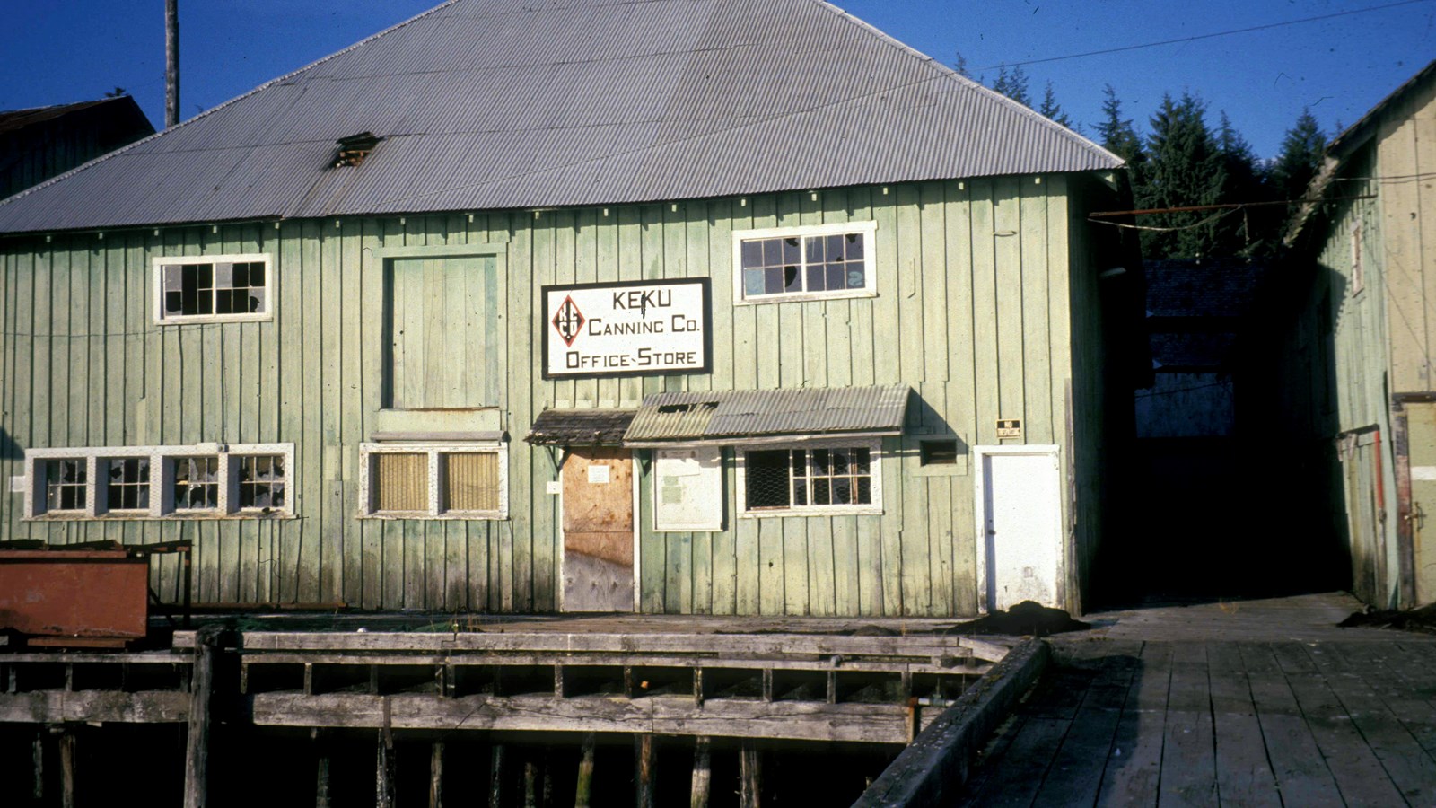 The Keku Cannery Office and Store in a faded green building on a pier.