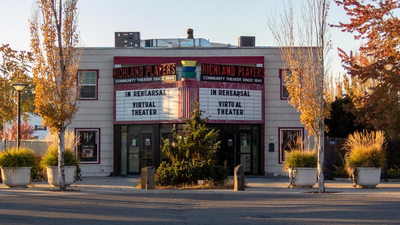 Color Photograph of a two story brick building with a colorful marquee displaying text.