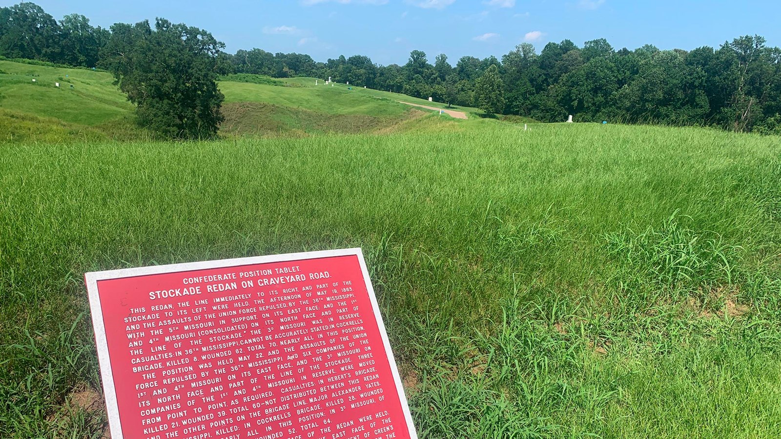 A large red sign explaining the events at Stockade Redan on top of the grassy fort.