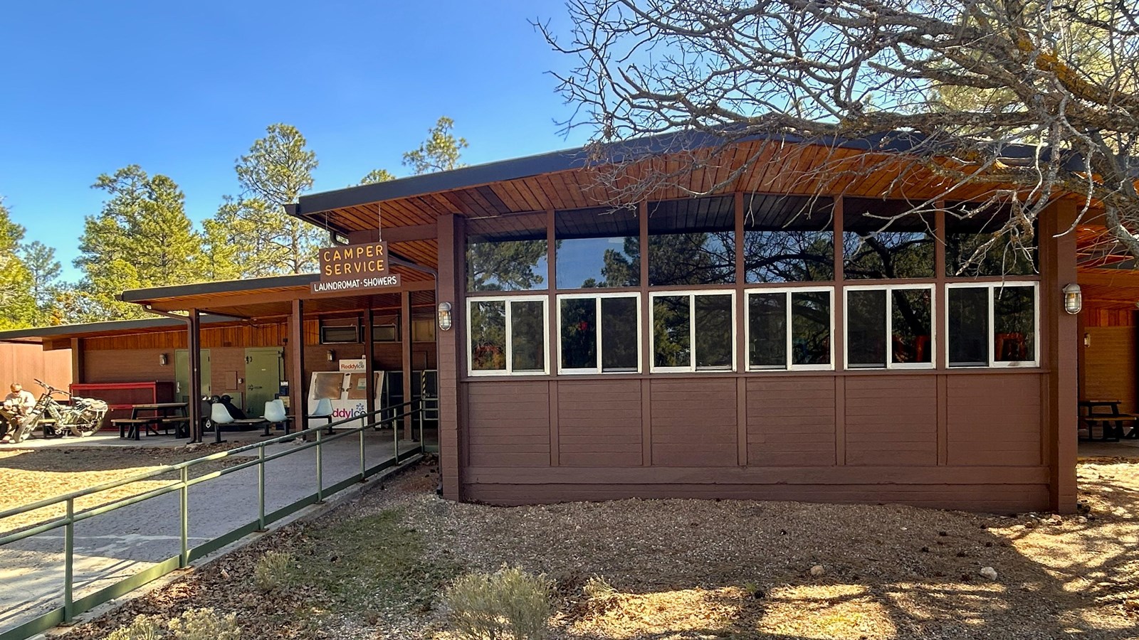 A brown building with a walkway and trees 