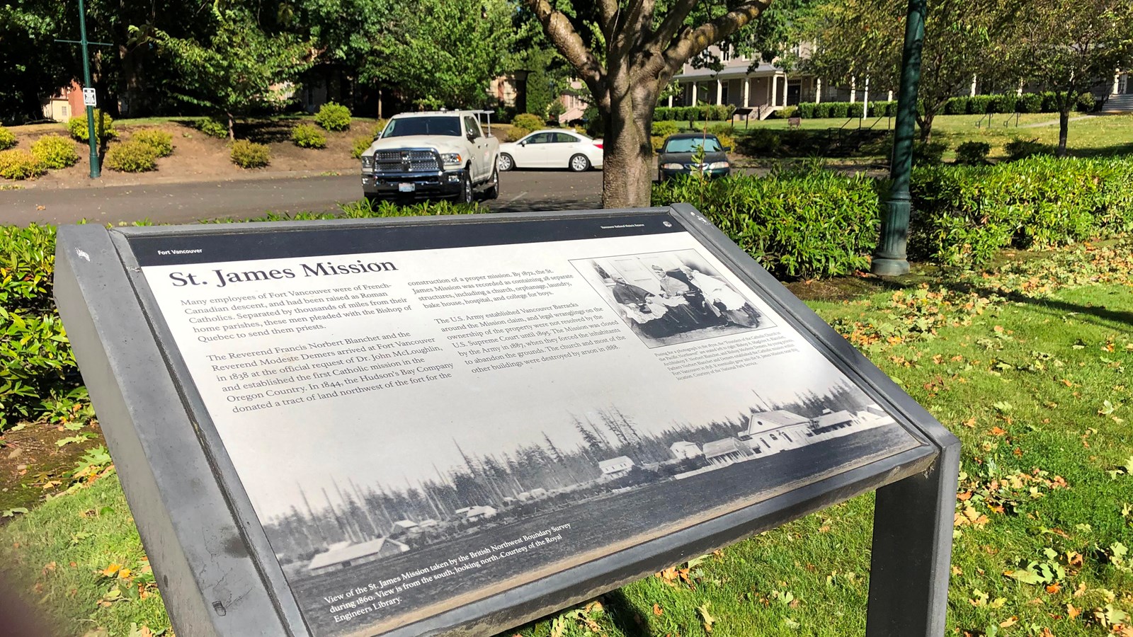 A sign near a parking lot and grassy areas.