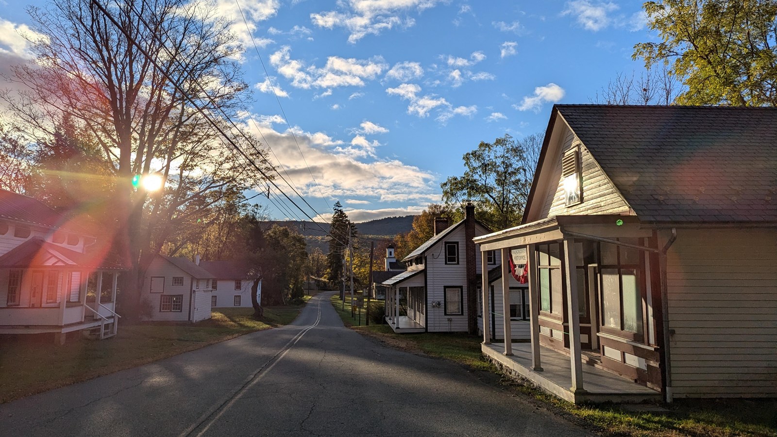 A street with 19th century buildings. There is a sun glare in the upper left of the photo.