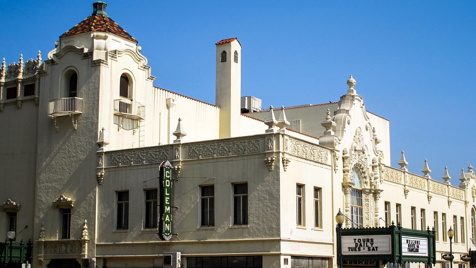 A large white building on a corner with intricate and ornate carvings, etchings, and architecture.