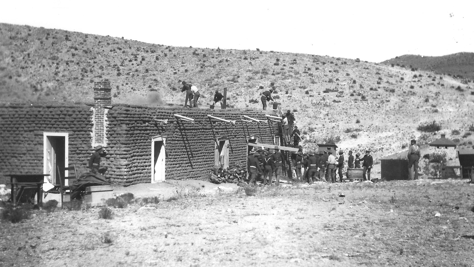 Black and white image of a block building on fire and soldiers putting out the blaze.