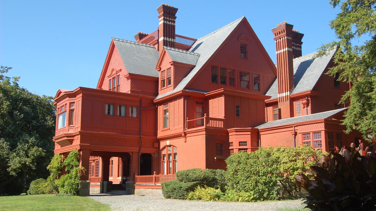 Red brick colored home on an expansive green lawn with trees