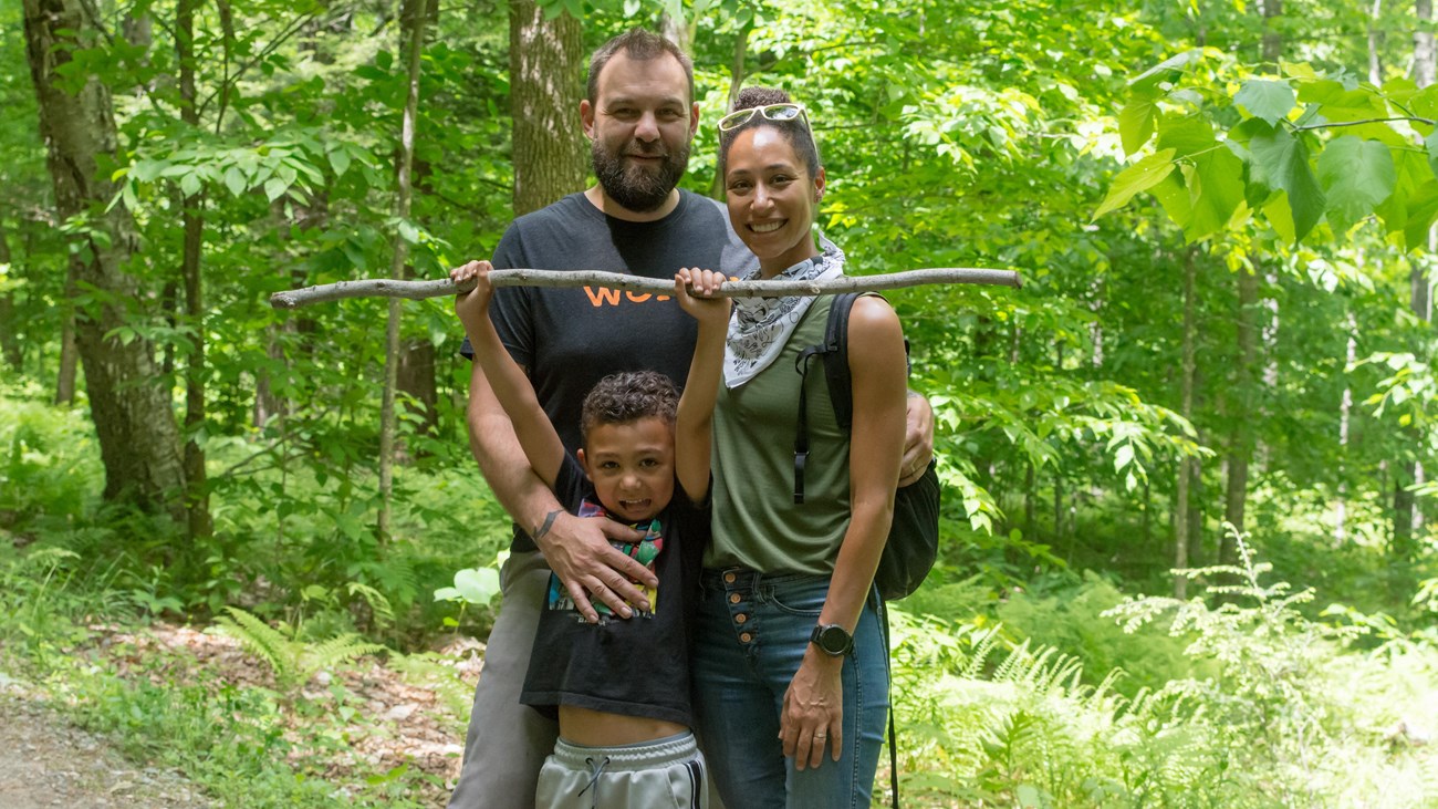 Two adults and one child on a trail pose for photo