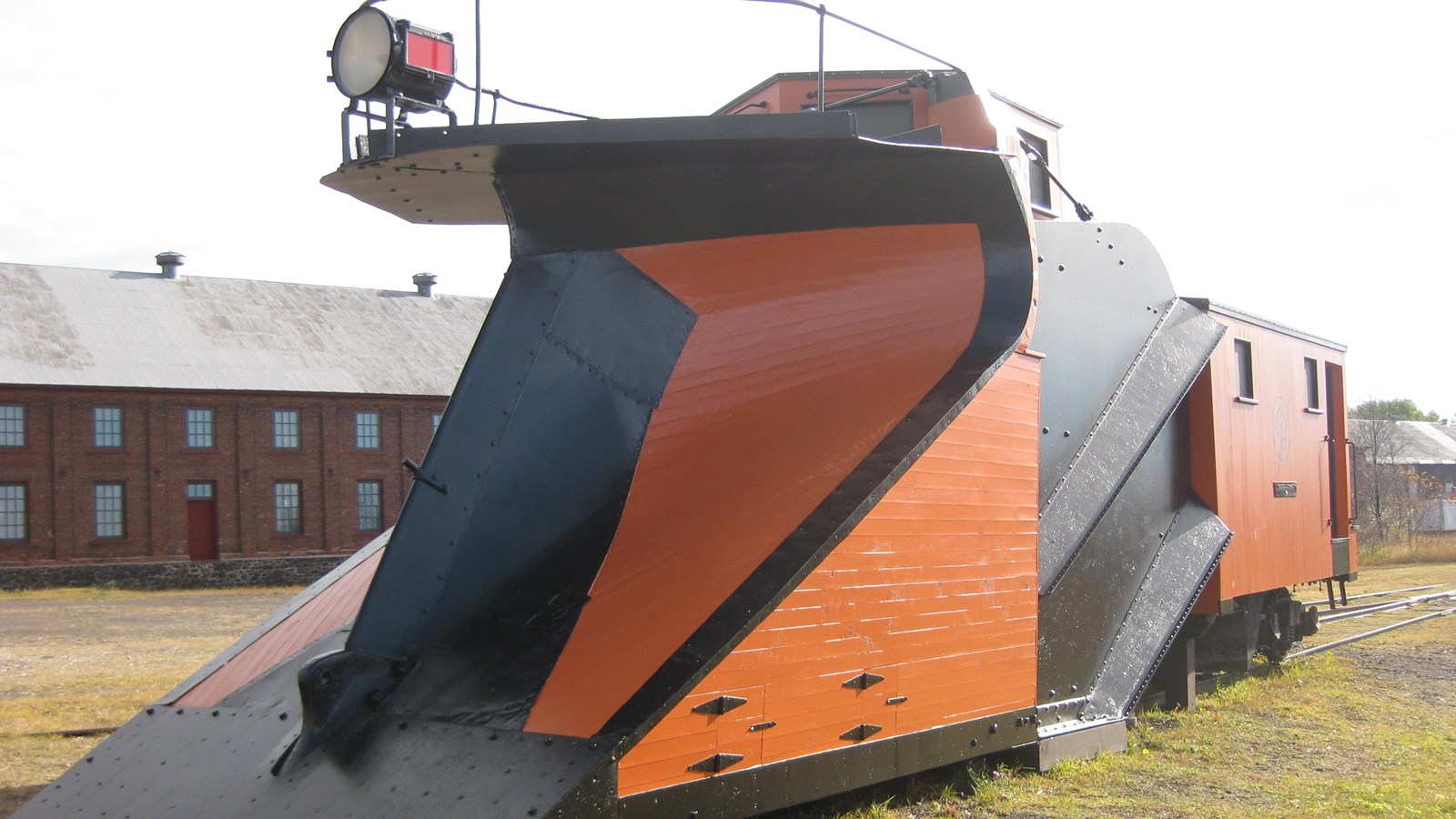 black and orange snow plow train on old rail tracks