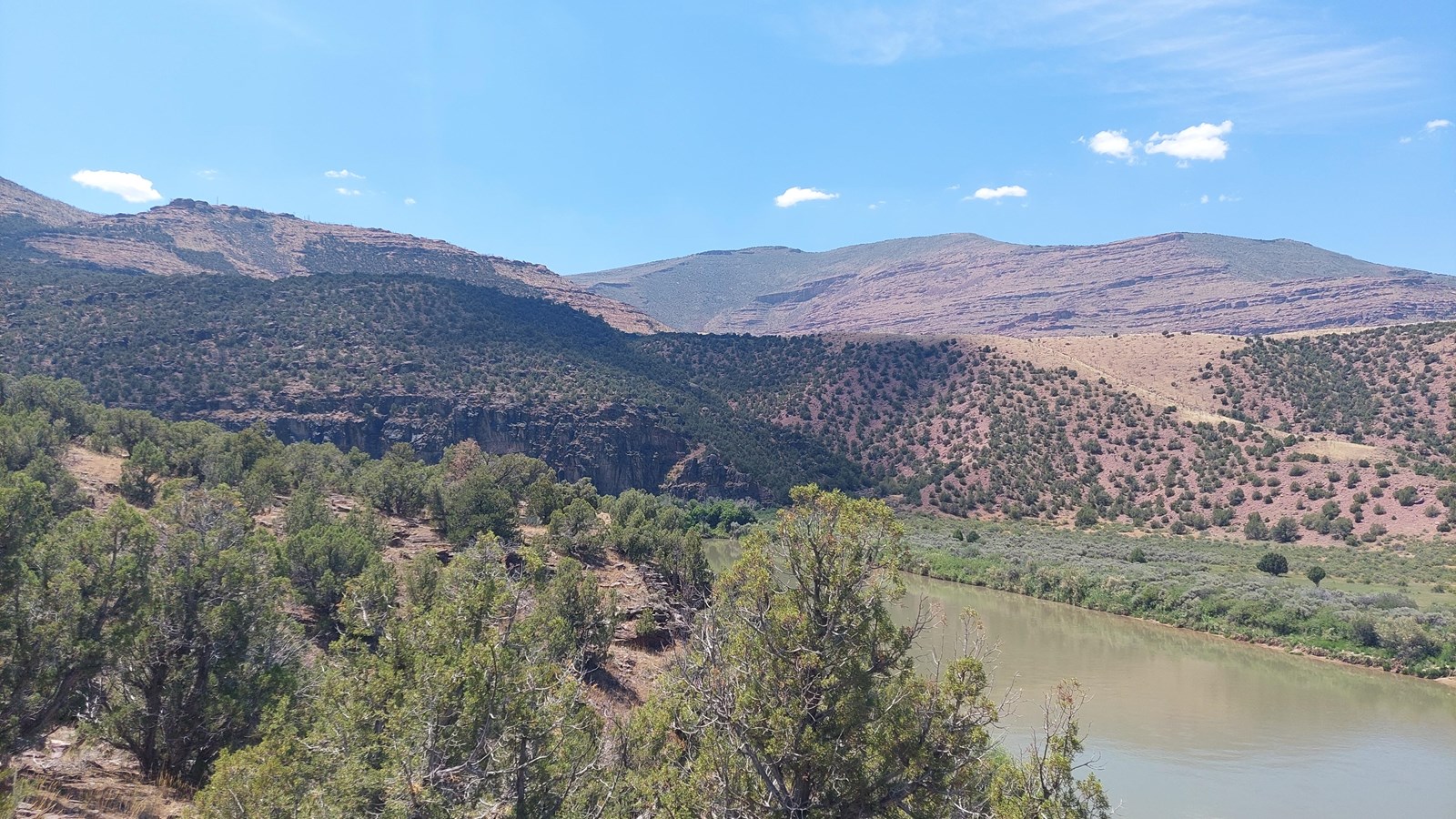 Large desert mountainsides with reddish soils, covered with small shrubs.