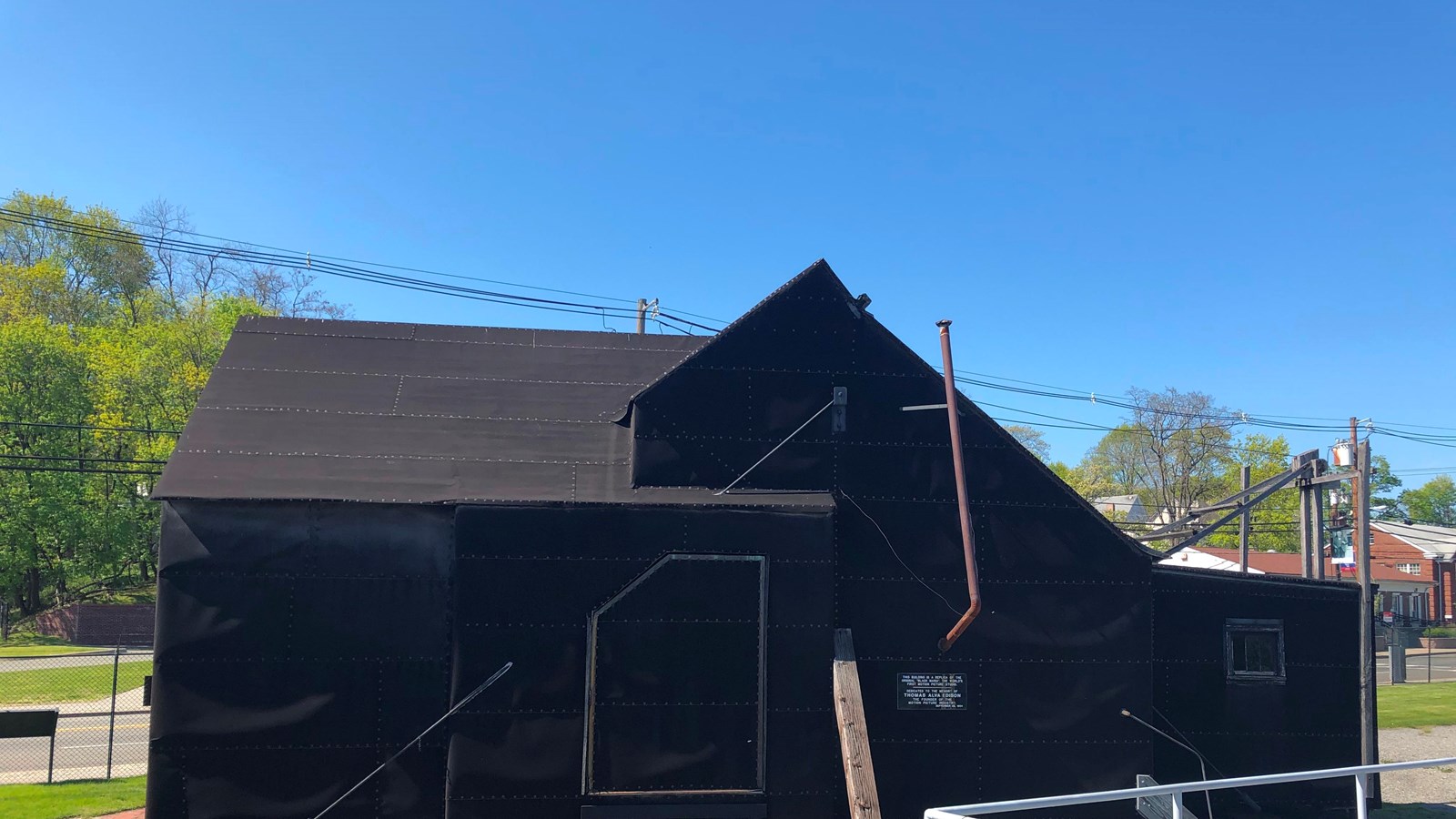 Angular, Black tar paper covered building. Sky, gravel and wooden track surround it.