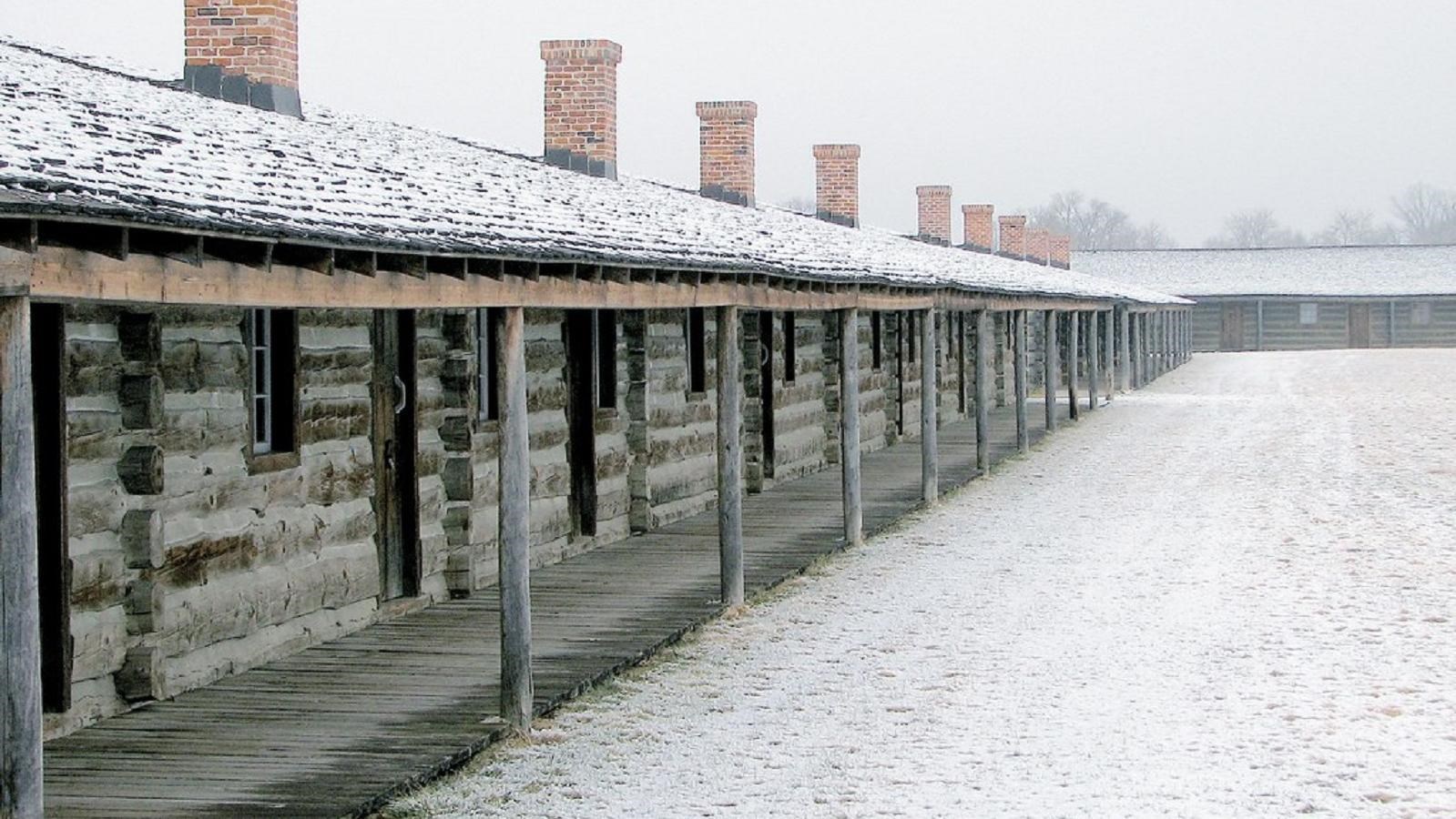 A series of split log buildings built in 1820 are dusted with snow
