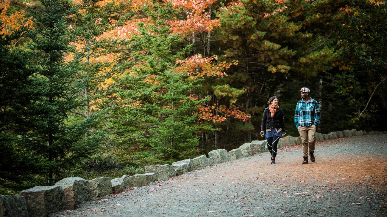 Two people walking along a crushed gravel surfaced road