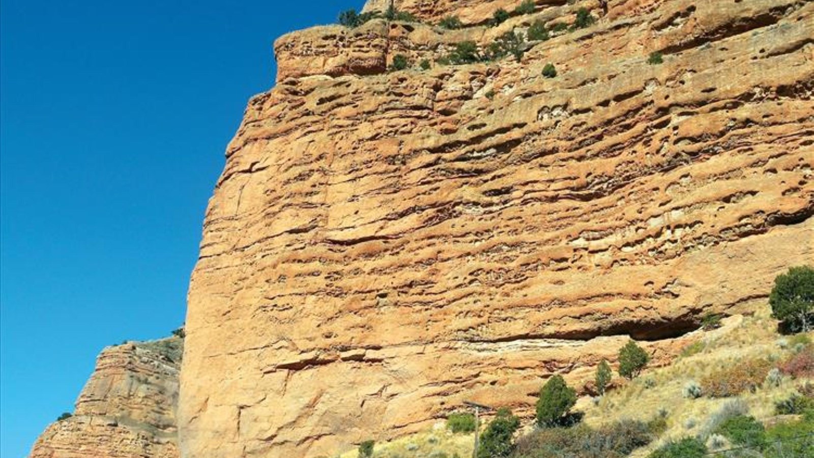 A rock monolith, littered with small holes.