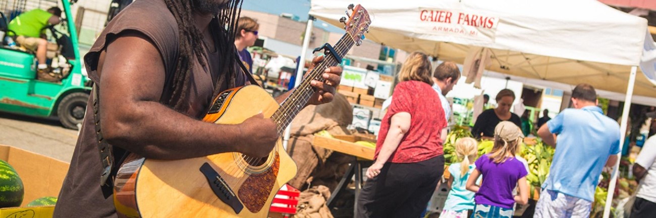 Man playing guitar at open market. 