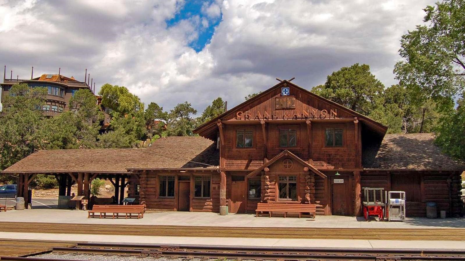 Along railroad tracks, a log building, mostly one story, with a two story section in the center.