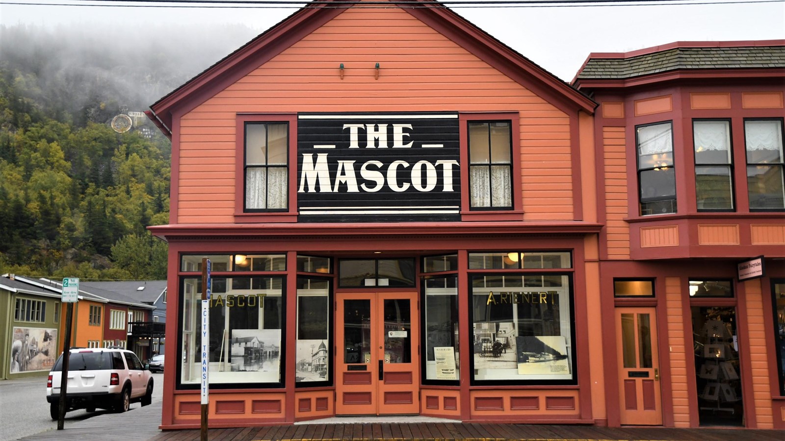  A two-story orange building with red trim. A black sign on the second story reads “The Mascot.