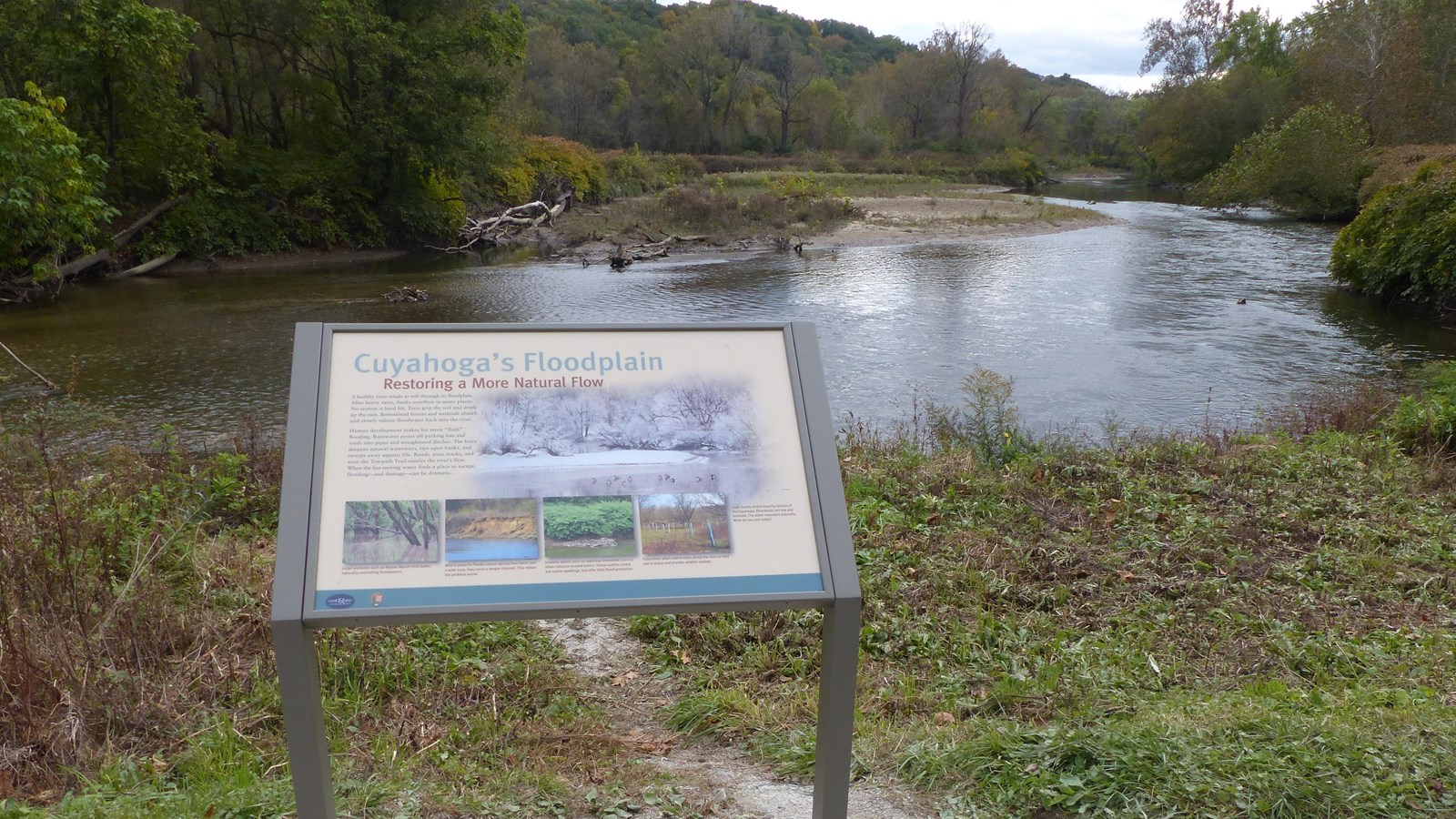 An exhibit overlooking a slow-moving river with forest in the distance.