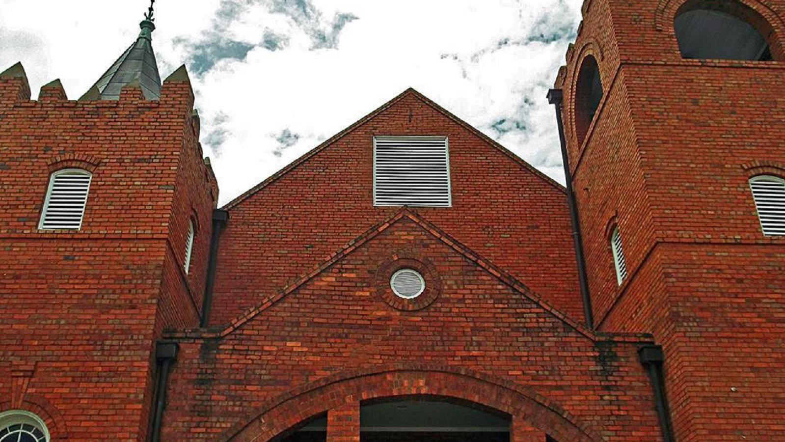 Red brick church with two tall spires. By Betty Rehberg, CC BY-SA 3.0