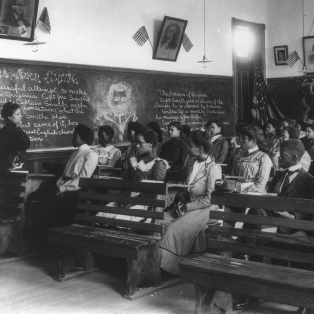 19th century African American students listen to African American teacher in classroom