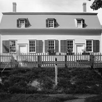 black and white photo of a white clapboard building with two doors