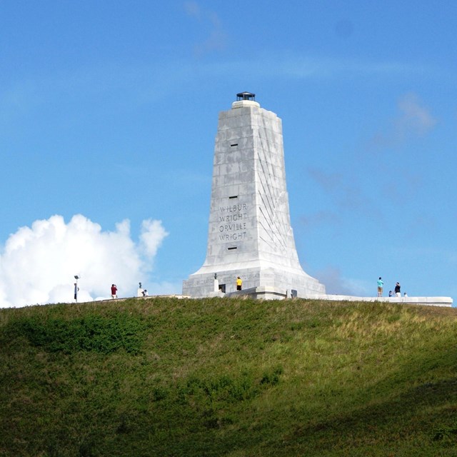 Granite monument atop grassy hill on sunny day