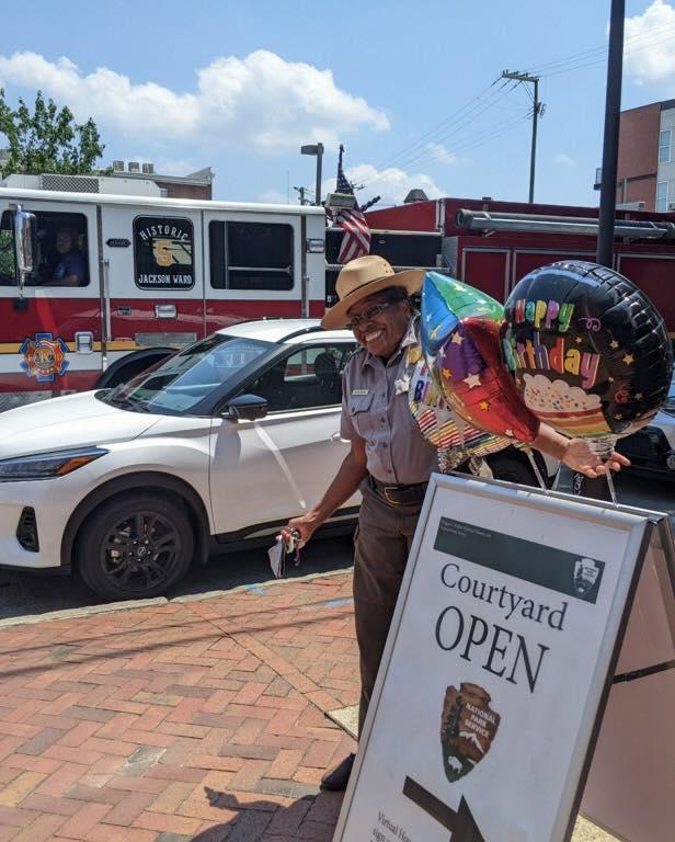 Woman standing next to a sandwich board and balloons