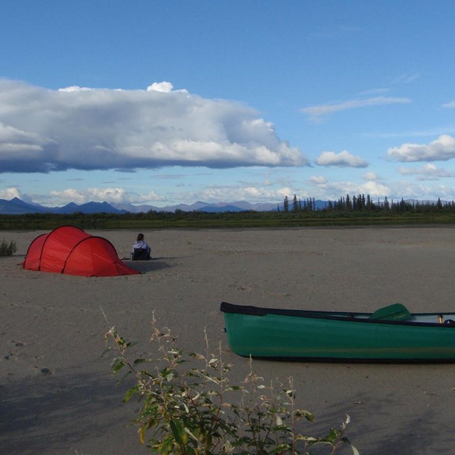 A campsite with a canoe on a beach.