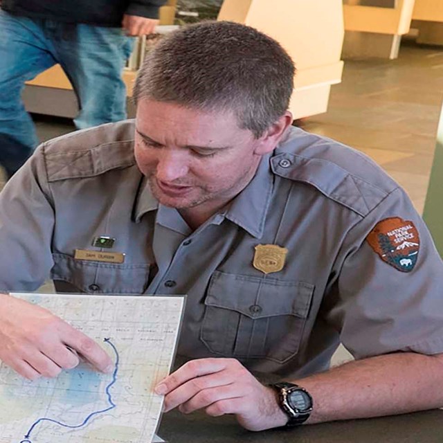 A National Park Service Ranger uses a map to mark a trail 