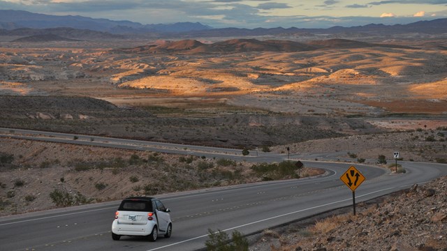 A car drives on a road through a desert.